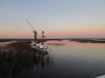 Two anglers fishing on a boat in a marsh
