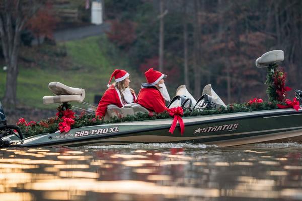 Two anglers in decorated Christmas boat dressed as Santa Claus and Mrs. Claus