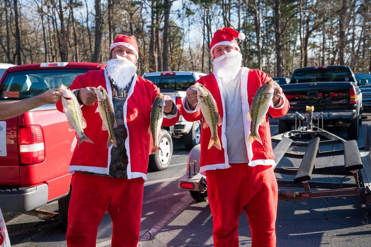 Two anglers dressed as Santa proudly holding up their catches