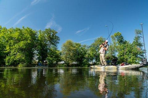 Angler standing on kayak reeling in fish