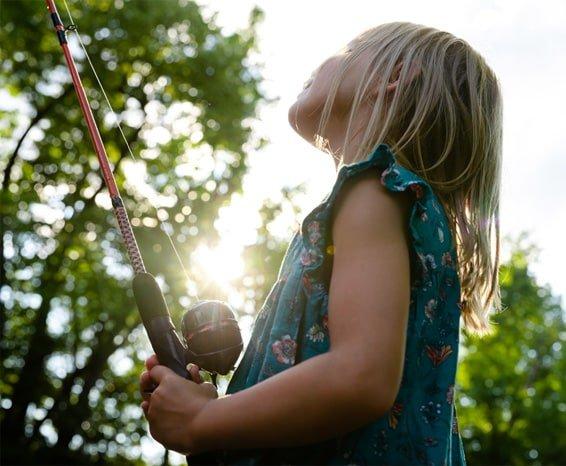 Young girl holding fishing rod and looking toward the sky